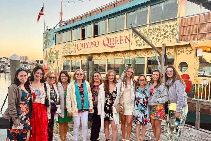 Group of people smiling on a dock with the Calypso Queen boat in the background.