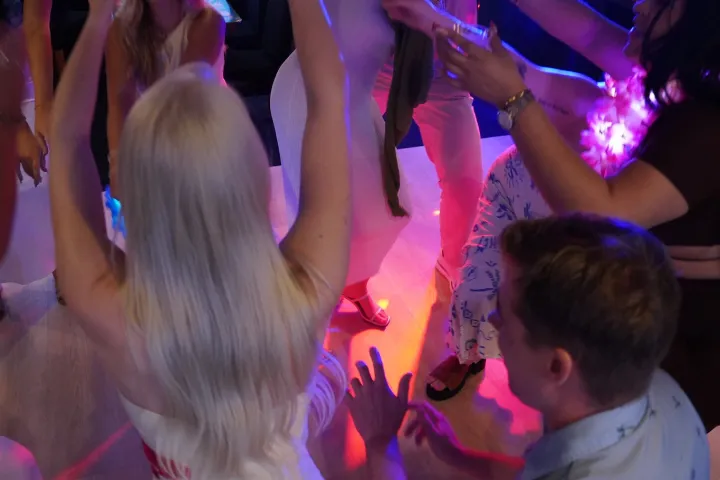 Group of people dancing in a dimly lit room with colorful lights.
