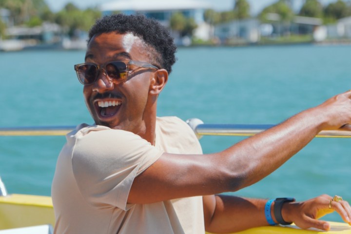 Man with sunglasses enjoying a boat ride, smiling and pointing.