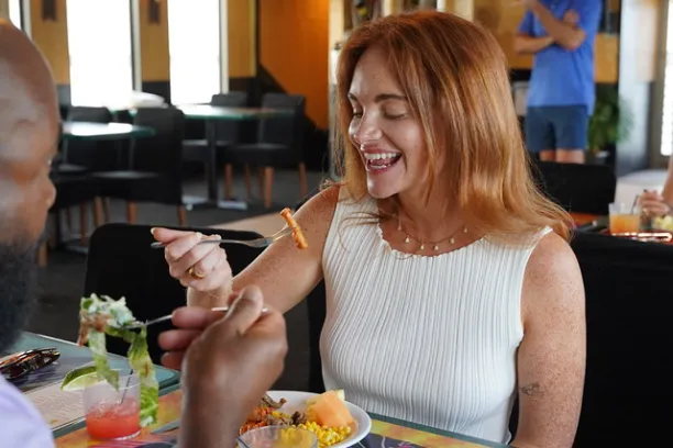 Two people dining on a colorful boat with drinks and food on the table.