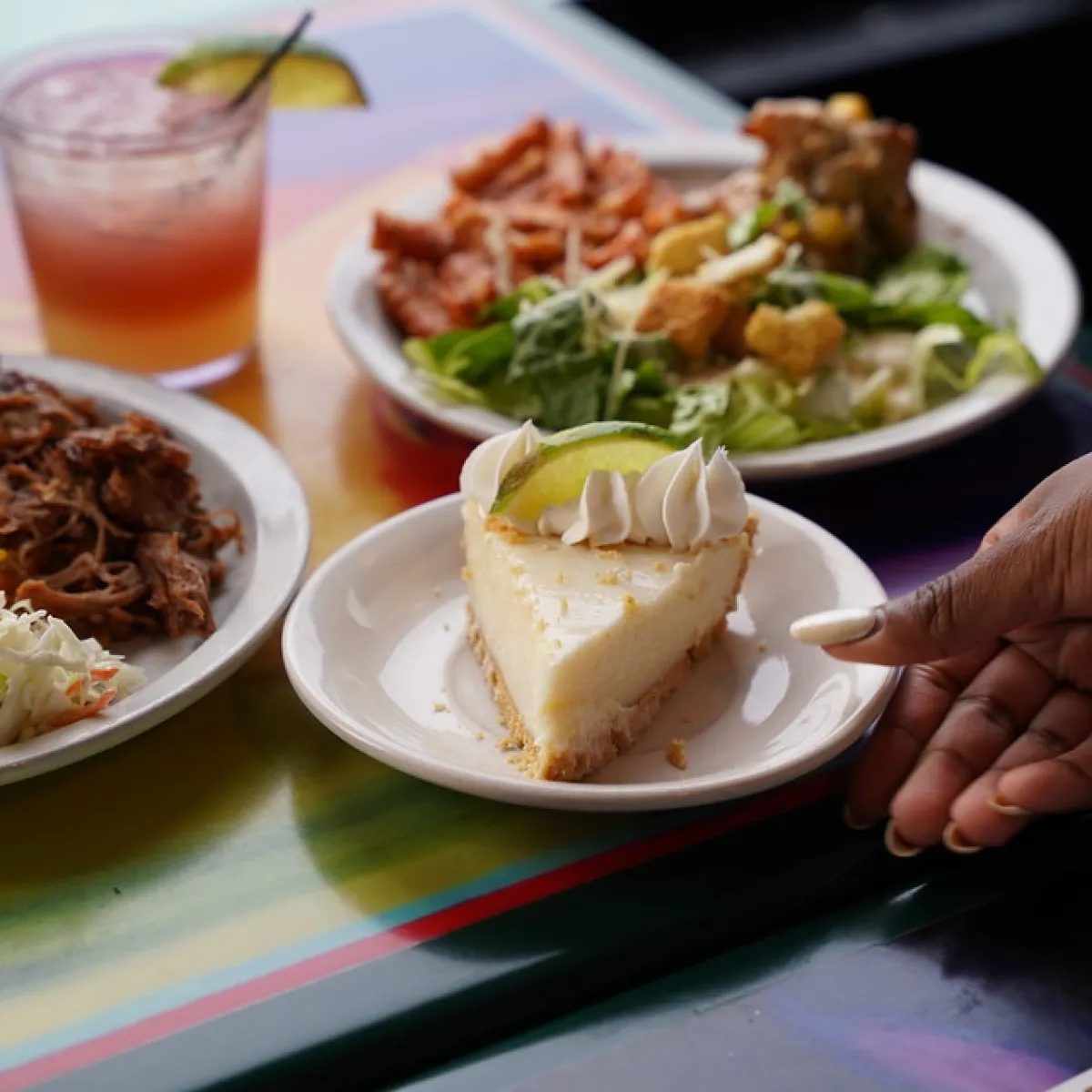 Slices of pie, salad, and drink on a colorful table.