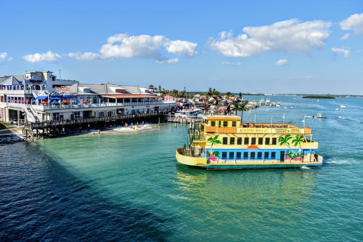 Colorful boat near a waterfront restaurant, with blue sky and scattered clouds.