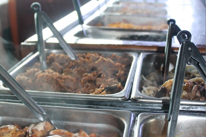 Steaming buffet trays with various cooked meats and tongs.