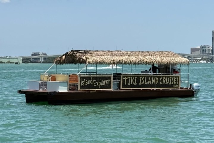 A tiki-themed cruise boat on water under a clear blue sky.