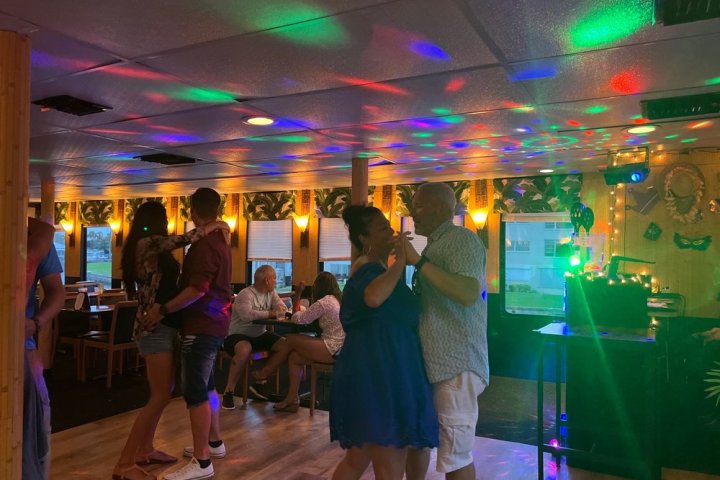 People dancing in a colorful, warmly lit room with disco lights.