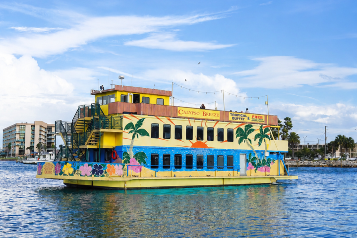 Colorful tropical-themed boat on clear blue water under a blue sky.
