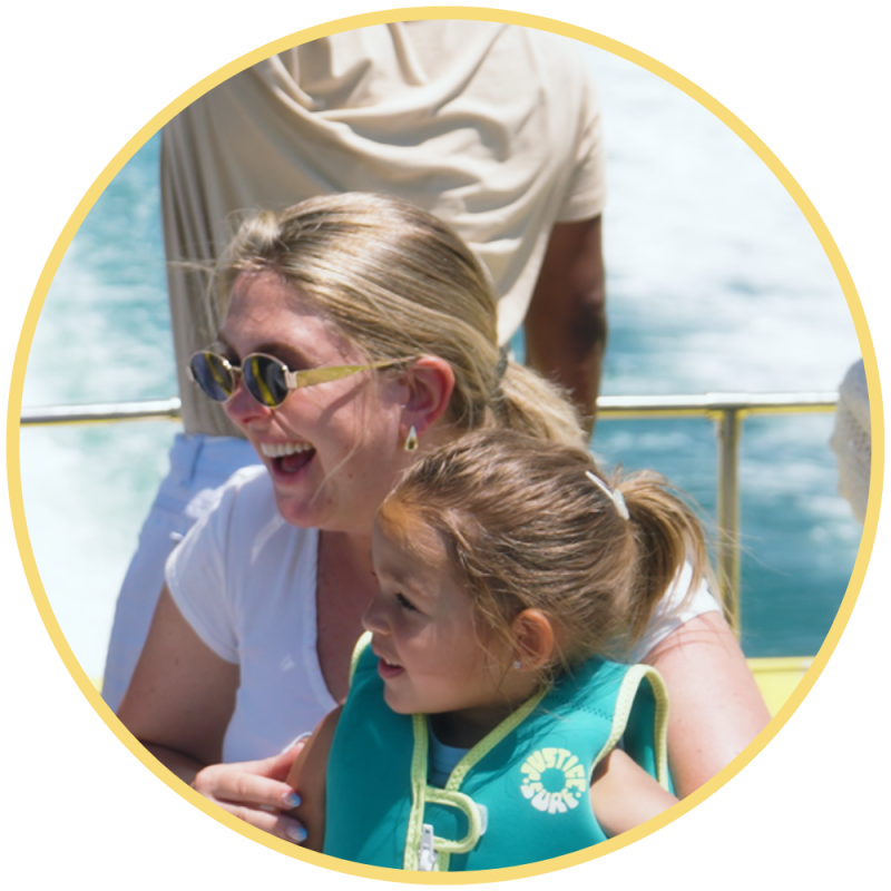 Woman and child smiling on a boat, with water in the background.