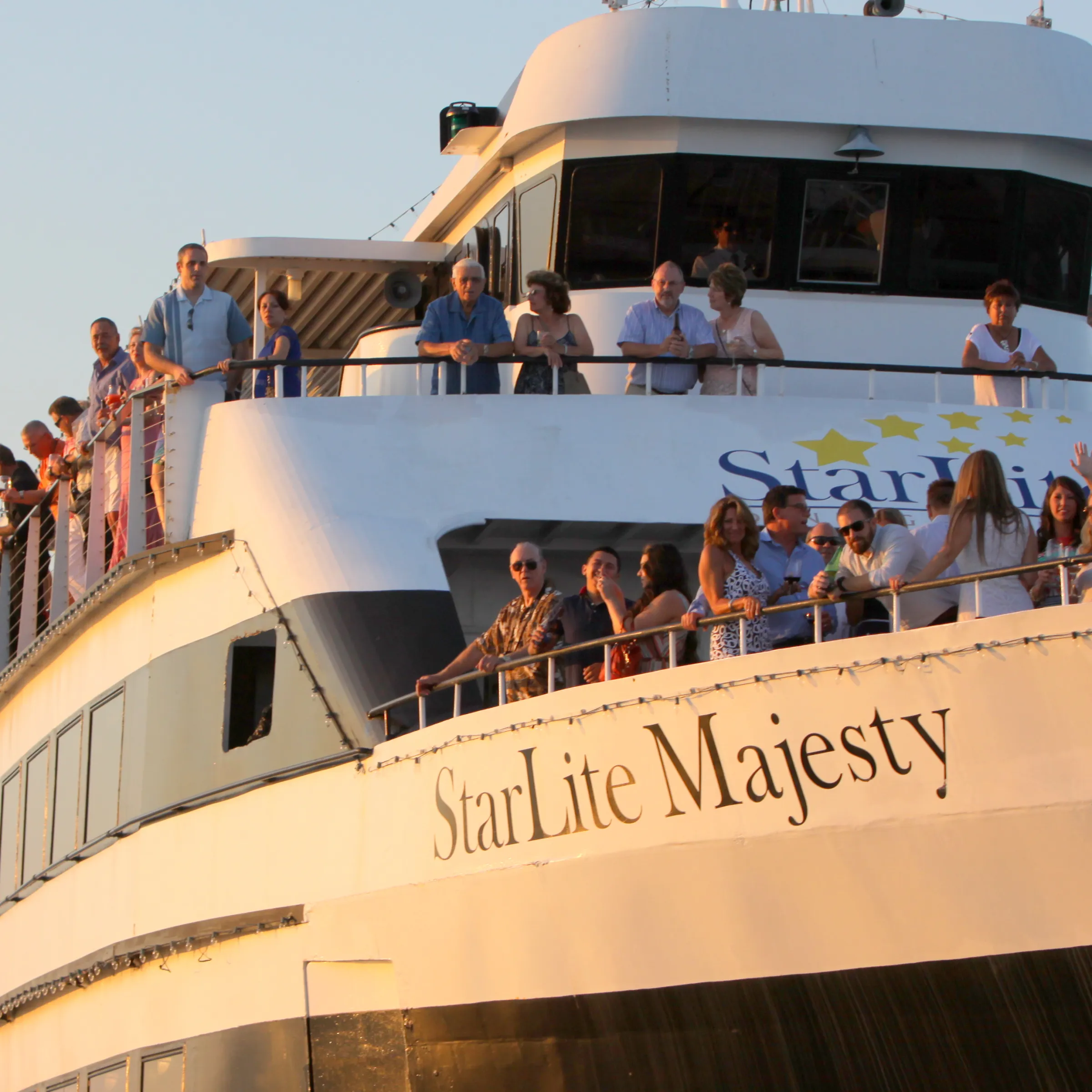 People on the deck of a boat named 'StarLite Majesty' during sunset.