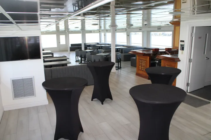 Spacious room with tall tables, bar area, and large windows.