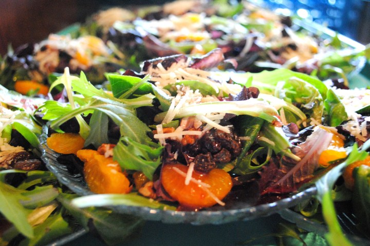 Fresh salad with greens, orange slices, raisins, nuts, and grated cheese.