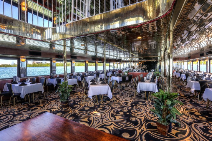 Elegant indoor dining area on a boat with large windows and elaborate decor.