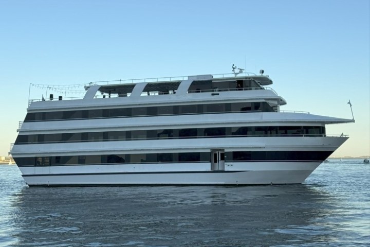 Large multi-deck yacht on calm water under a clear sky.