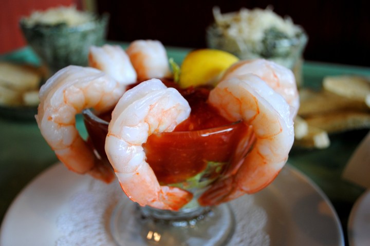 Shrimp cocktail with a lemon wedge in a glass bowl.