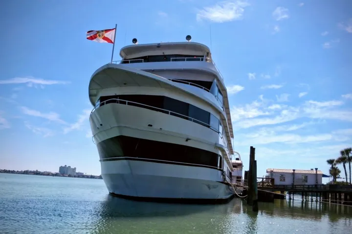 Large yacht docked on calm water under clear blue sky.