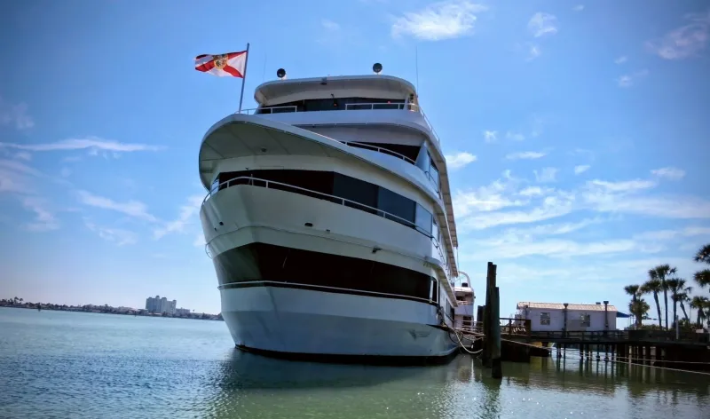 Large yacht docked on calm water under clear blue sky.