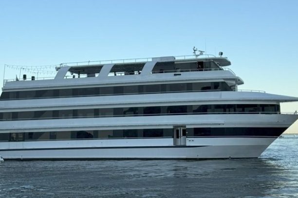 Large white multi-deck yacht on calm water.