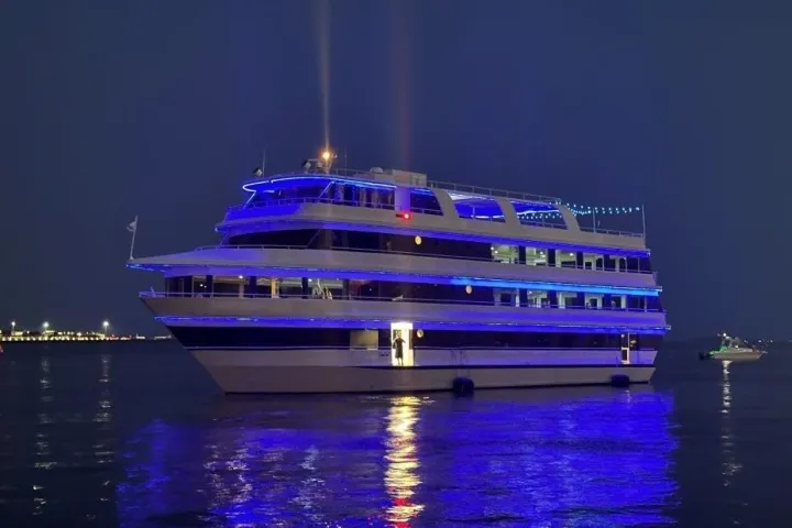 A large yacht with blue lights reflecting on the water at night.