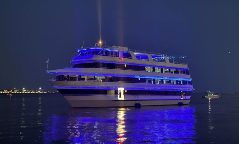 A large yacht with blue lights reflecting on the water at night.