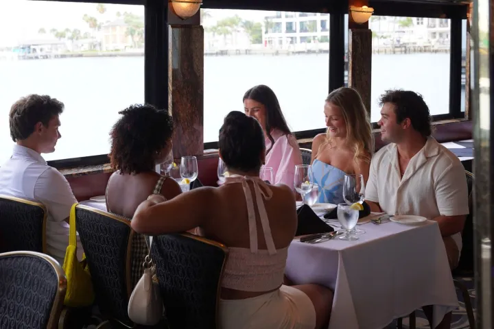 Group of people dining in a restaurant with waterfront view.