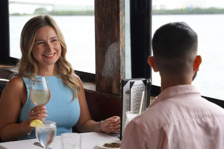 Woman smiling at man in a restaurant with river view.