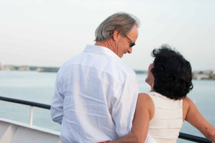 Couple embracing on a boat deck with a scenic water view.