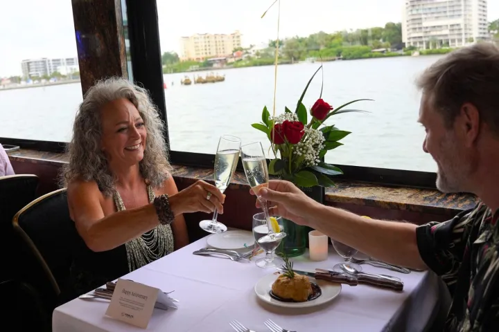 Couple toasting at a restaurant with a river view.