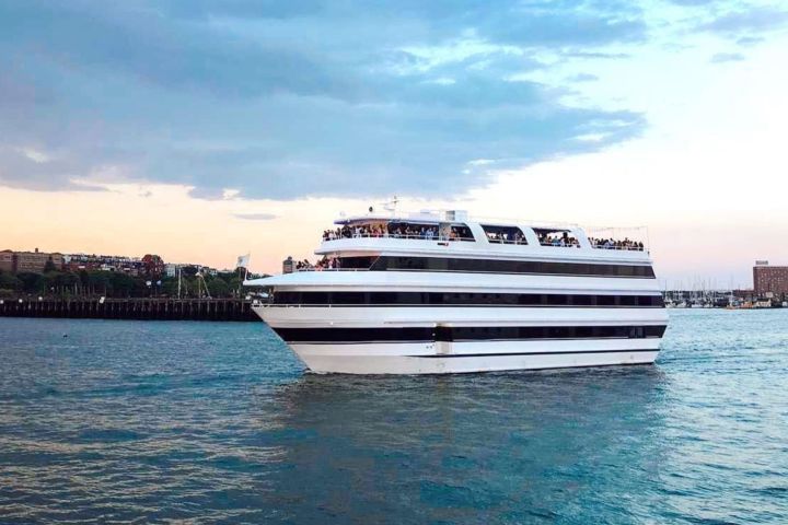 A large white cruise ship sailing on a calm body of water under a partly cloudy sky.