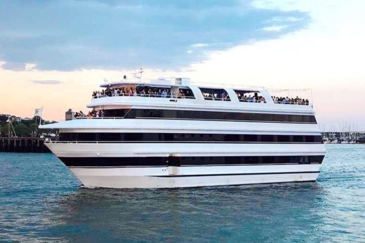 Large white cruise ship on blue water under cloudy sky.