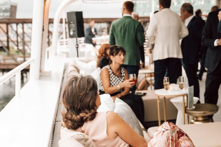 People socializing on a boat deck with drinks and elegant attire.