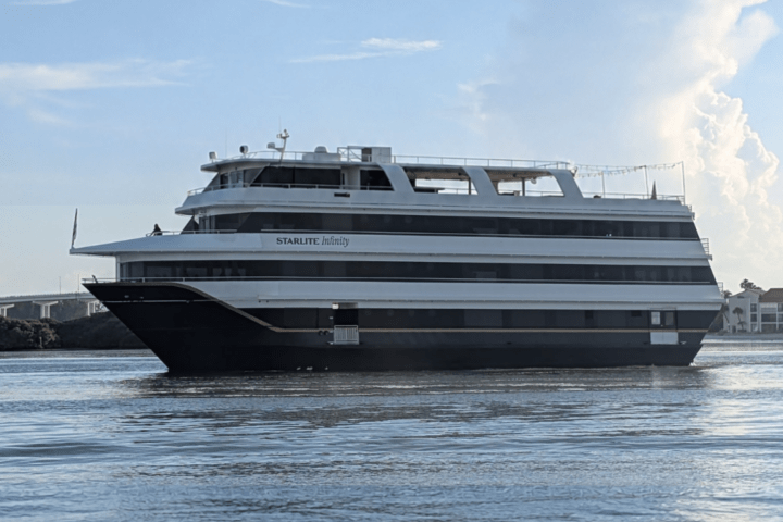 Large yacht cruising on a calm river, against a clear sky.