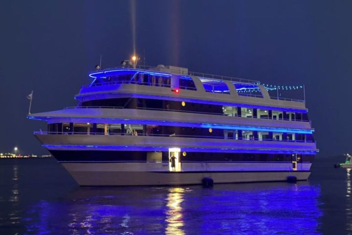 Large yacht illuminated with blue lights on water at night.