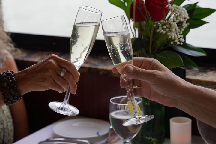 Two people toasting with champagne glasses at a restaurant table.
