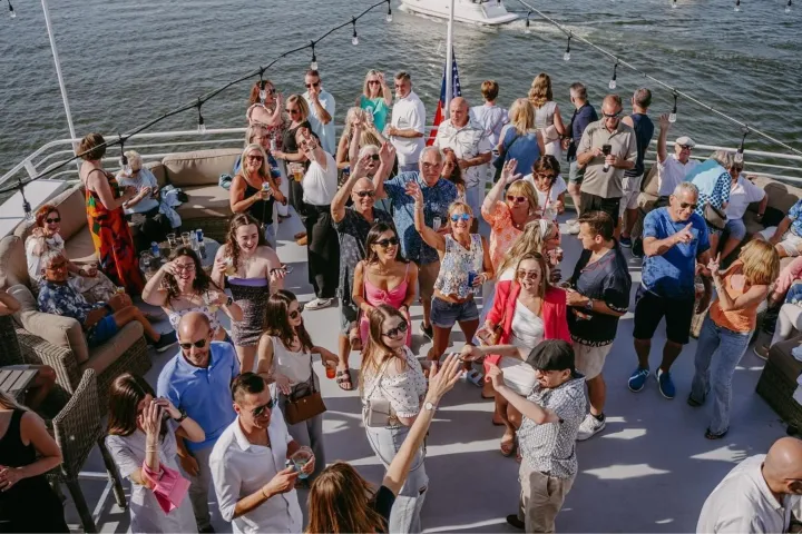 Group of people celebrating on a boat with decorations and water in the background.