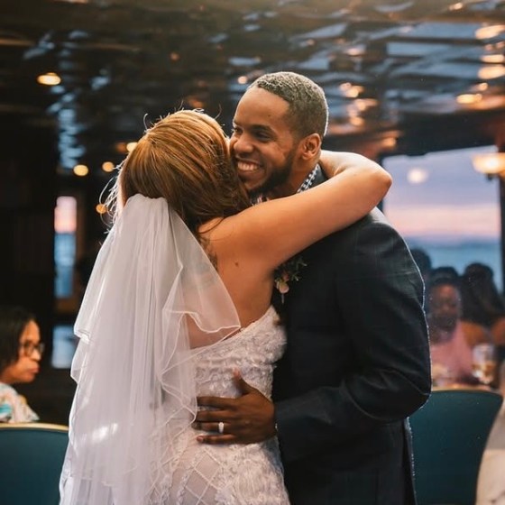 Bride and groom embrace and smile at each other during wedding reception.