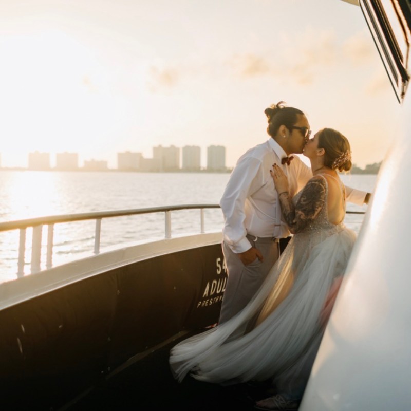 Couple kissing on a boat at sunset with city skyline in the background.