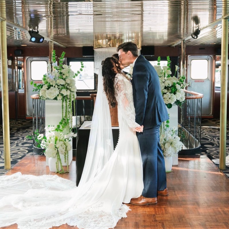 Bride and groom kissing at indoor wedding altar with flowers.