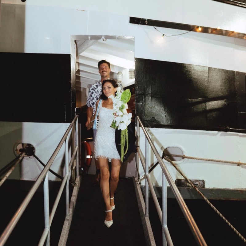 Couple walking down a ramp from a ship, woman holding flowers.