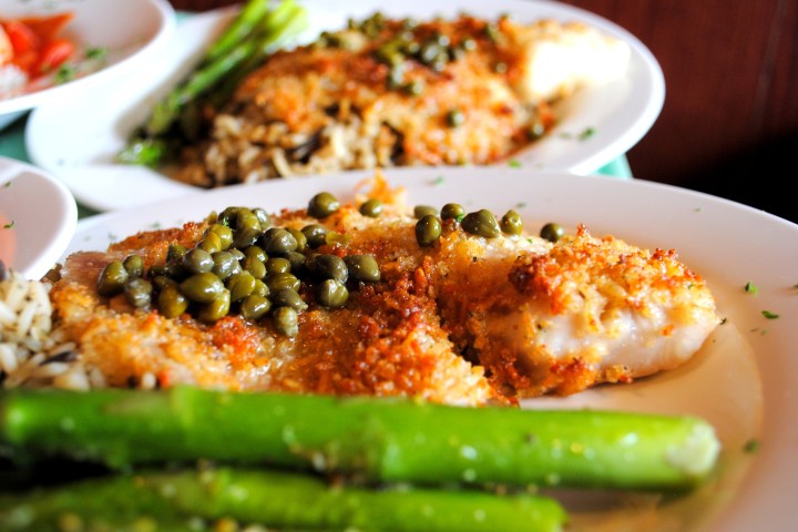 Fish fillet with capers, asparagus, and rice on plates.